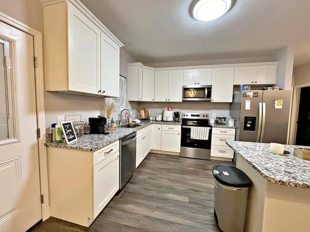 kitchen featuring a sink, light stone countertops, appliances with stainless steel finishes, and white cabinetry