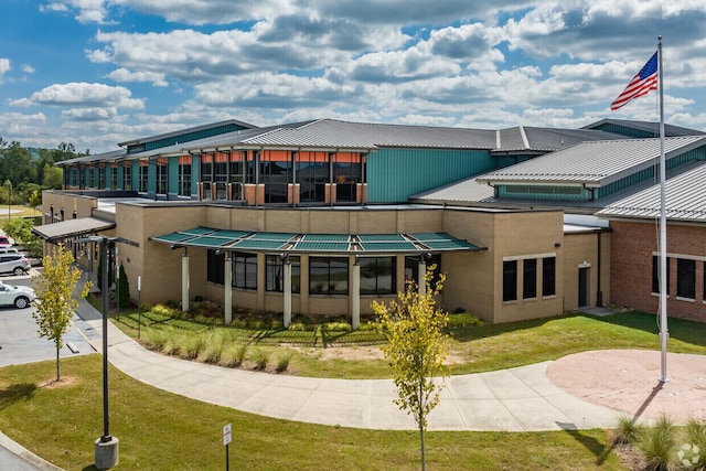 rear view of property with metal roof, a lawn, and stucco siding