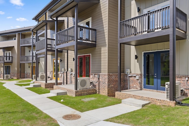 exterior space featuring brick siding, central AC unit, board and batten siding, and french doors