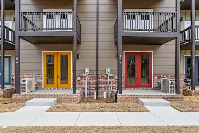 entrance to property featuring french doors, ac unit, and brick siding