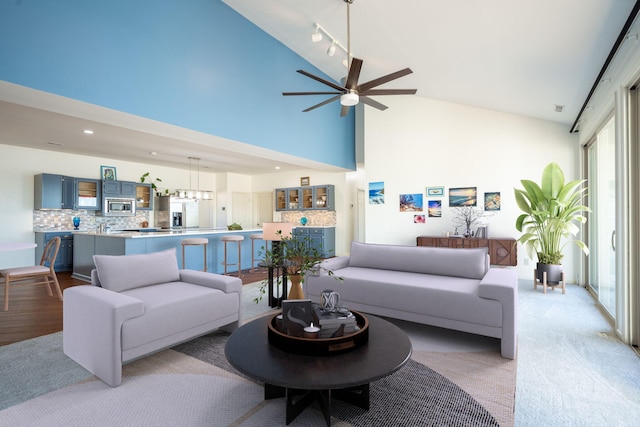 living room with ceiling fan, rail lighting, and high vaulted ceiling