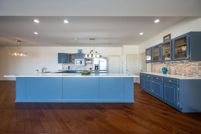 kitchen with appliances with stainless steel finishes, pendant lighting, blue cabinets, and a spacious island