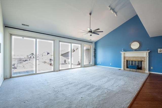 unfurnished living room with ceiling fan, rail lighting, a tile fireplace, and vaulted ceiling