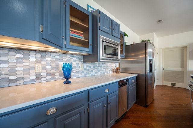 kitchen with dark wood-type flooring, appliances with stainless steel finishes, decorative backsplash, and blue cabinets