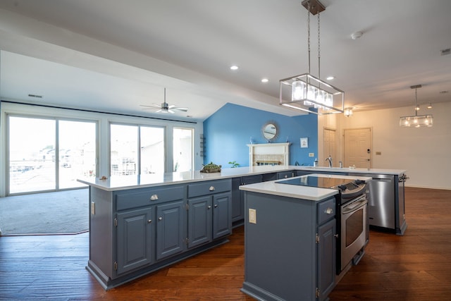 kitchen featuring kitchen peninsula, ceiling fan, appliances with stainless steel finishes, pendant lighting, and a center island