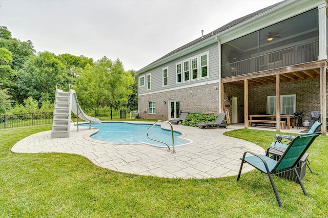 view of pool featuring a water slide, a yard, ceiling fan, a sunroom, and a patio area