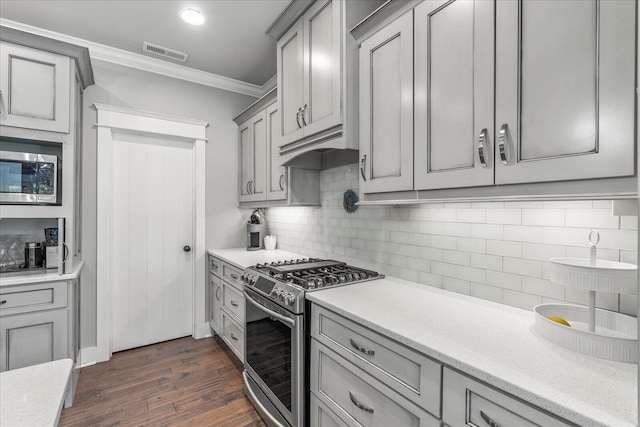 kitchen featuring gray cabinetry, tasteful backsplash, ornamental molding, dark hardwood / wood-style floors, and stainless steel appliances