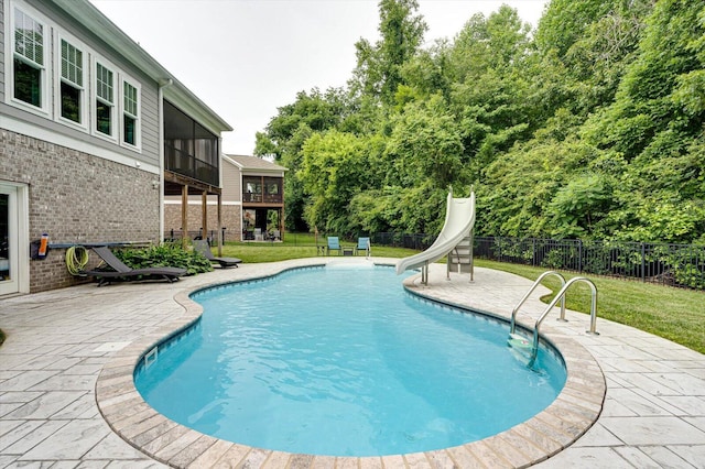 view of swimming pool featuring a yard, a patio area, a sunroom, and a water slide