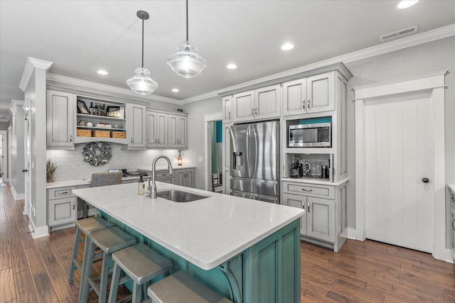 kitchen featuring hanging light fixtures, appliances with stainless steel finishes, sink, and a center island with sink