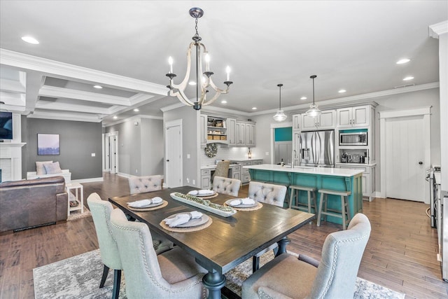 dining space featuring an inviting chandelier, a brick fireplace, ornamental molding, dark hardwood / wood-style flooring, and beam ceiling