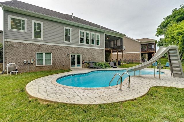 view of pool with a yard, a sunroom, a patio, and a water slide