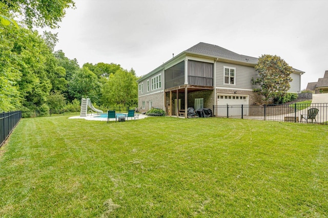 rear view of house with a garage, a patio area, a lawn, a fenced in pool, and a sunroom