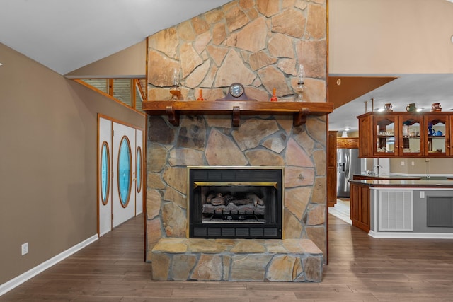 681 Pinhook Rd, Calhoun, TN 37309 - unfurnished living room with wood finished floors, baseboards, lofted ceiling, a sink, and a stone fireplace