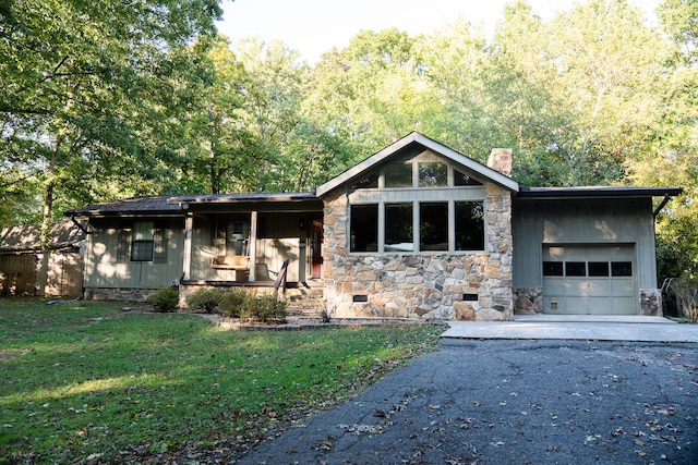 view of front of property featuring covered porch, a front yard, and a garage