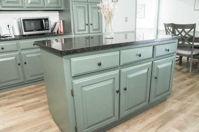 kitchen featuring green cabinets, a center island, dark stone countertops, and light hardwood / wood-style floors