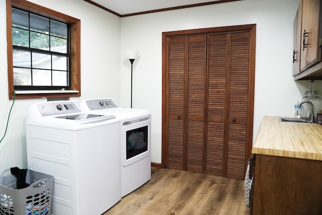 laundry area with sink, cabinets, light hardwood / wood-style flooring, crown molding, and washer and dryer