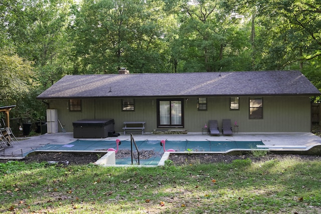 rear view of property featuring a patio area and a hot tub