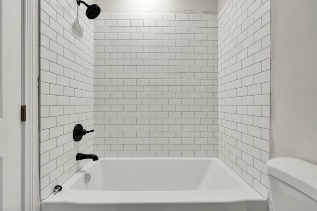 bathroom featuring tiled shower / bath combo and toilet