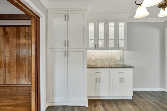 bar with decorative backsplash, hanging light fixtures, white cabinets, and dark stone counters