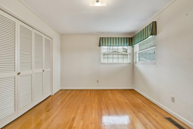 unfurnished bedroom featuring wood-type flooring, a closet, and crown molding