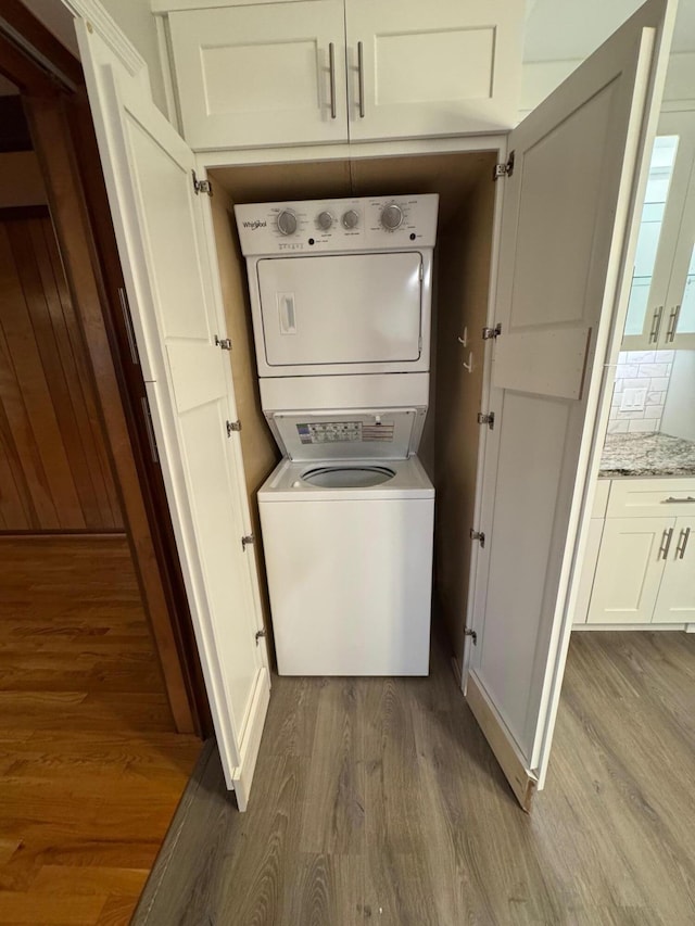 laundry area with hardwood / wood-style floors and stacked washer / dryer