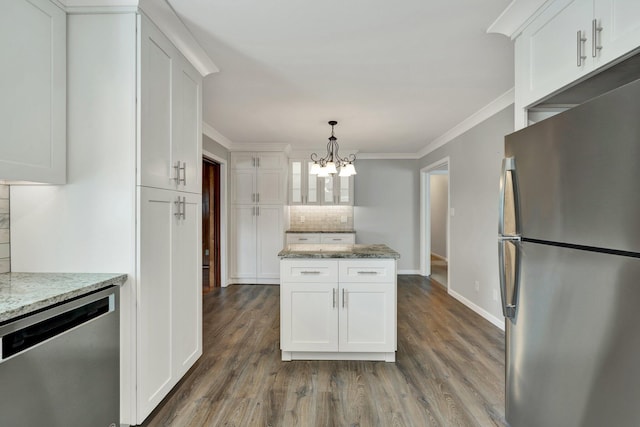 kitchen featuring light stone countertops, backsplash, stainless steel appliances, decorative light fixtures, and white cabinetry