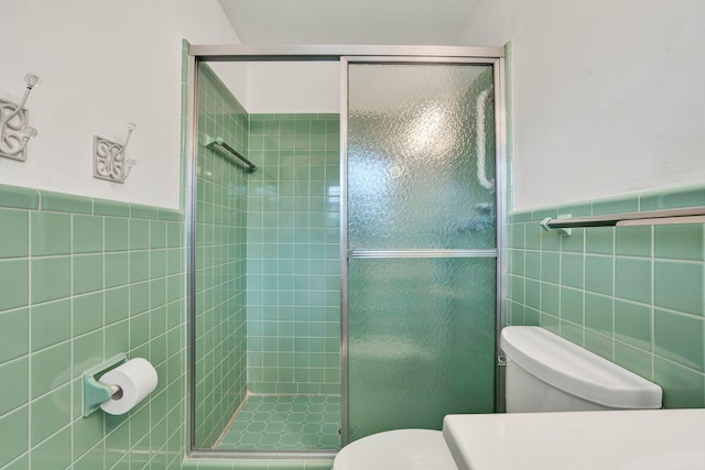 bathroom with toilet, an enclosed shower, and tile walls