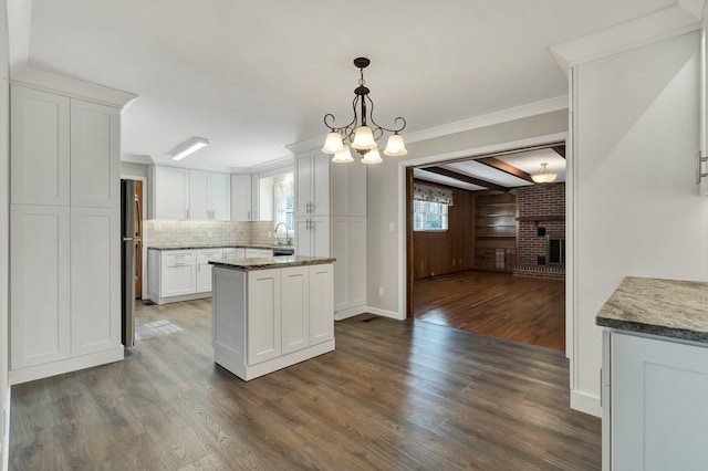 kitchen featuring white cabinetry, pendant lighting, dark hardwood / wood-style floors, and a brick fireplace