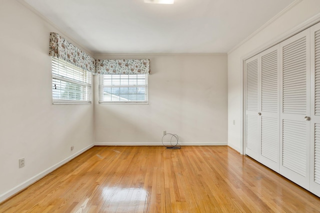 unfurnished bedroom featuring hardwood / wood-style flooring, ornamental molding, and a closet