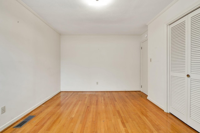 unfurnished bedroom with light wood-type flooring, crown molding, and a closet