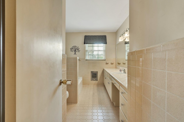 bathroom with heating unit, a bathing tub, vanity, and tile walls