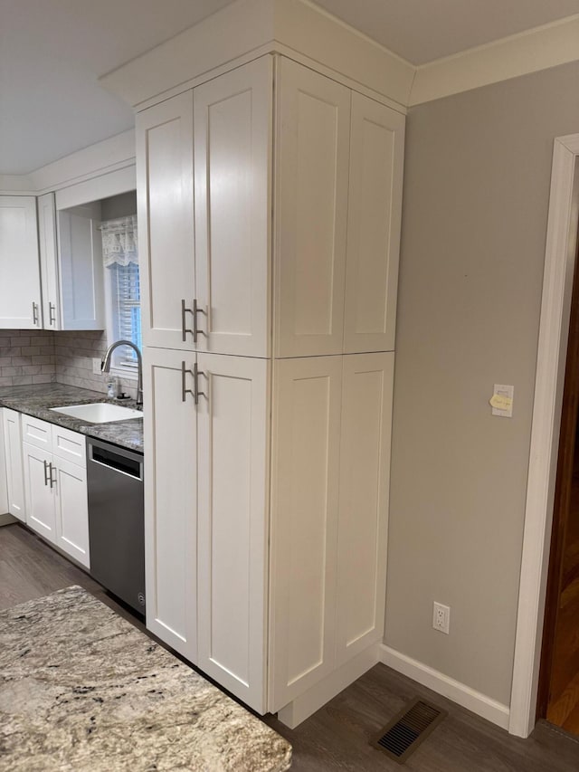 kitchen with light stone countertops, tasteful backsplash, stainless steel dishwasher, sink, and white cabinets