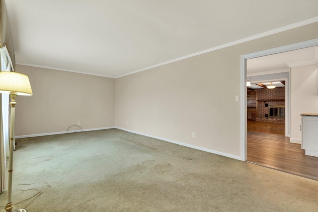 spare room with ornamental molding, carpet floors, and a brick fireplace