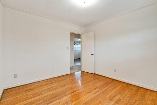 spare room featuring light wood-type flooring and crown molding