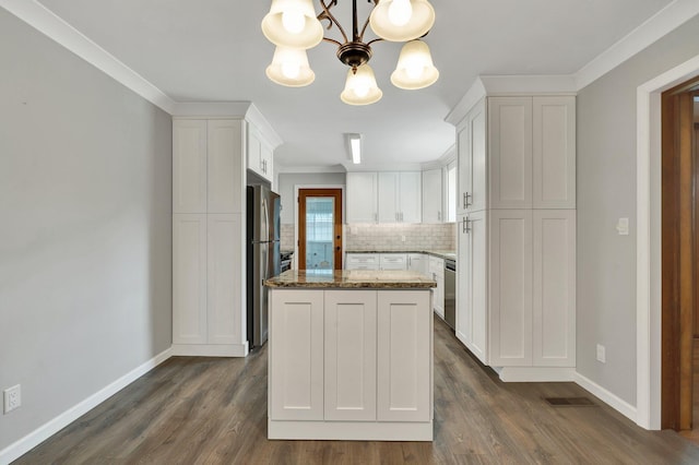 kitchen with stainless steel appliances, a kitchen island, pendant lighting, dark stone countertops, and white cabinetry