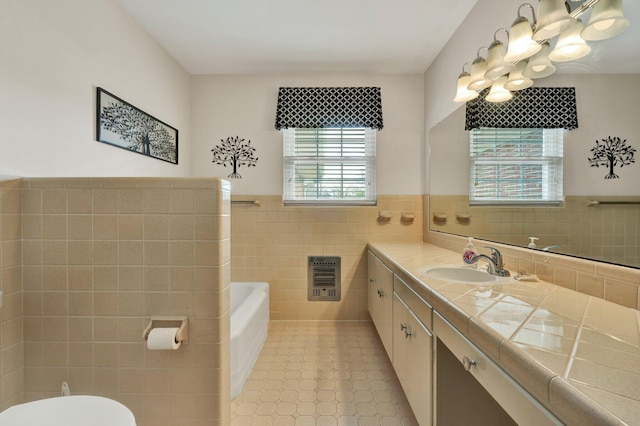 bathroom featuring tile patterned flooring, heating unit, toilet, vanity, and tile walls