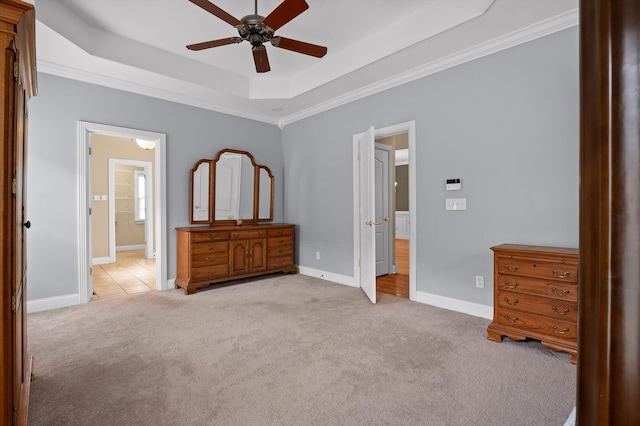 bedroom featuring ensuite bathroom, a tray ceiling, ornamental molding, light carpet, and baseboards
