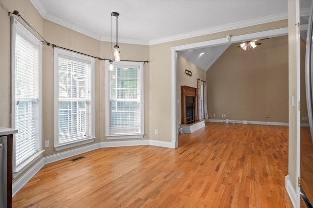 unfurnished dining area with visible vents, baseboards, a fireplace with raised hearth, light wood-type flooring, and a ceiling fan