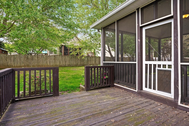 wooden deck featuring a sunroom, fence, and a lawn