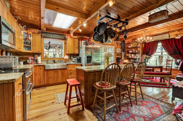 362 River Run Rd, Calhoun, TN 37309 - kitchen featuring appliances with stainless steel finishes, light wood finished floors, a sink, brown cabinetry, and beamed ceiling
