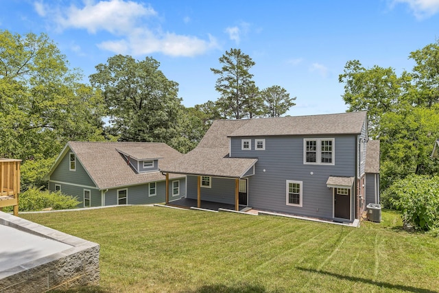 rear view of house featuring central AC and a lawn