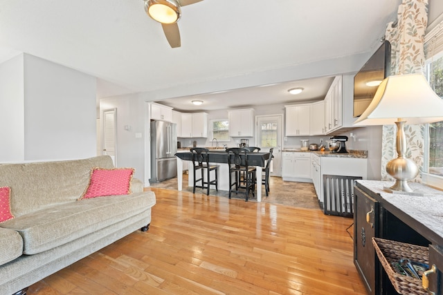 living room with ceiling fan, light hardwood / wood-style flooring, and sink