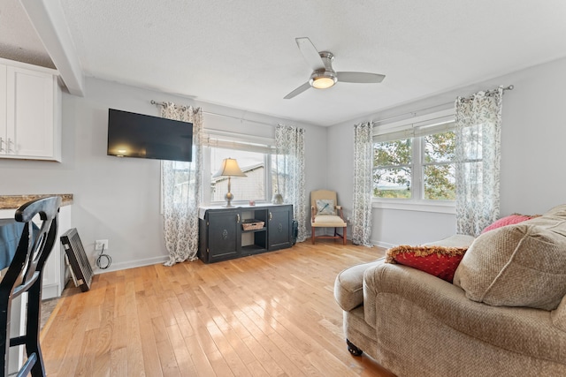 living room featuring a textured ceiling, light hardwood / wood-style flooring, and ceiling fan