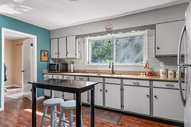 kitchen with white cabinets, appliances with stainless steel finishes, dark hardwood / wood-style flooring, and sink