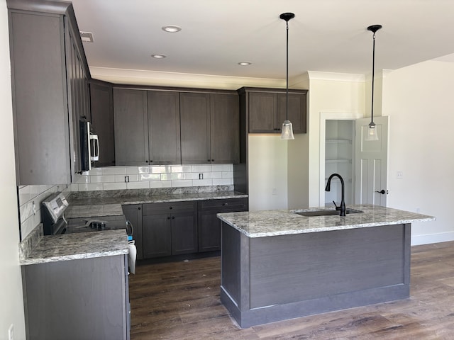 2901 Bobo Ave NW, Cleveland, TN 37312 - kitchen with appliances with stainless steel finishes, dark wood finished floors, decorative backsplash, light stone counters, and a center island with sink