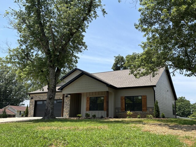 2901 Bobo Ave NW, Cleveland, TN 37312 - view of front facade featuring board and batten siding, an attached garage, stone siding, a front yard, and a shingled roof