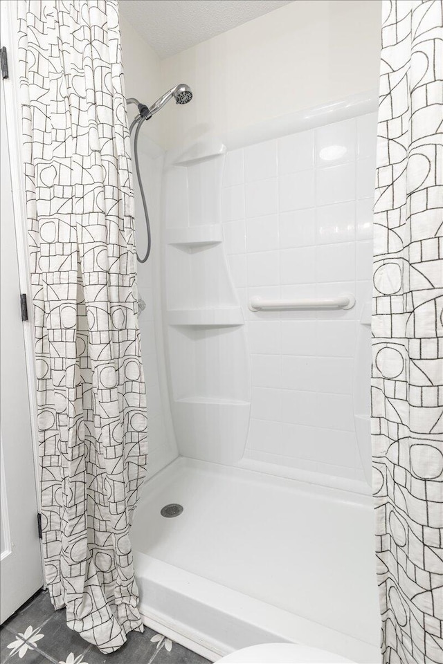 bathroom featuring a shower with shower curtain and a textured ceiling