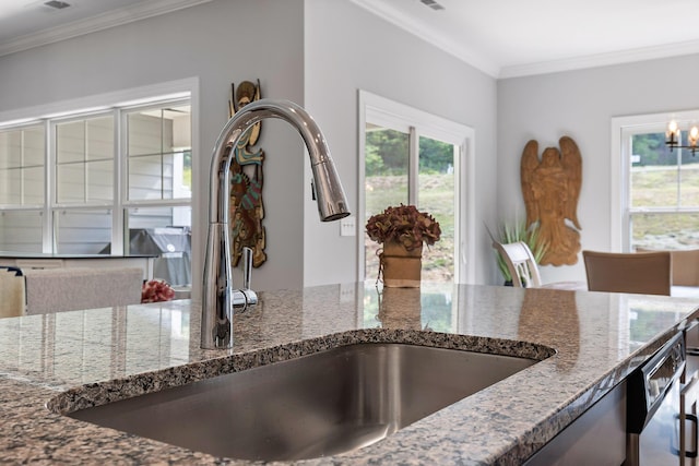 kitchen featuring sink, dishwasher, a notable chandelier, crown molding, and dark stone counters