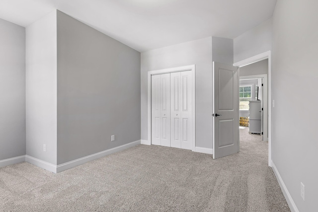 unfurnished bedroom with light colored carpet and a closet