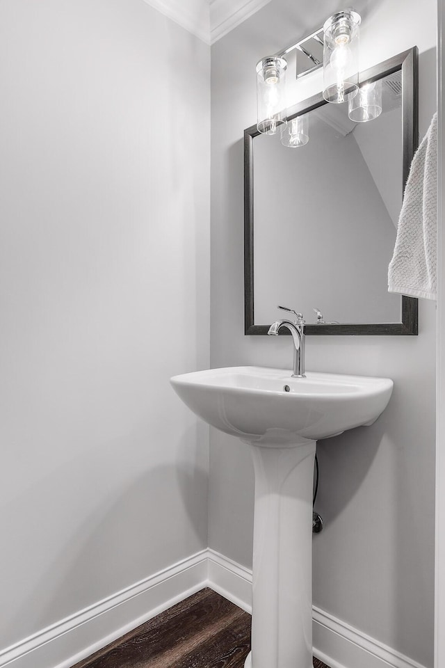 bathroom with wood-type flooring, ornamental molding, and sink